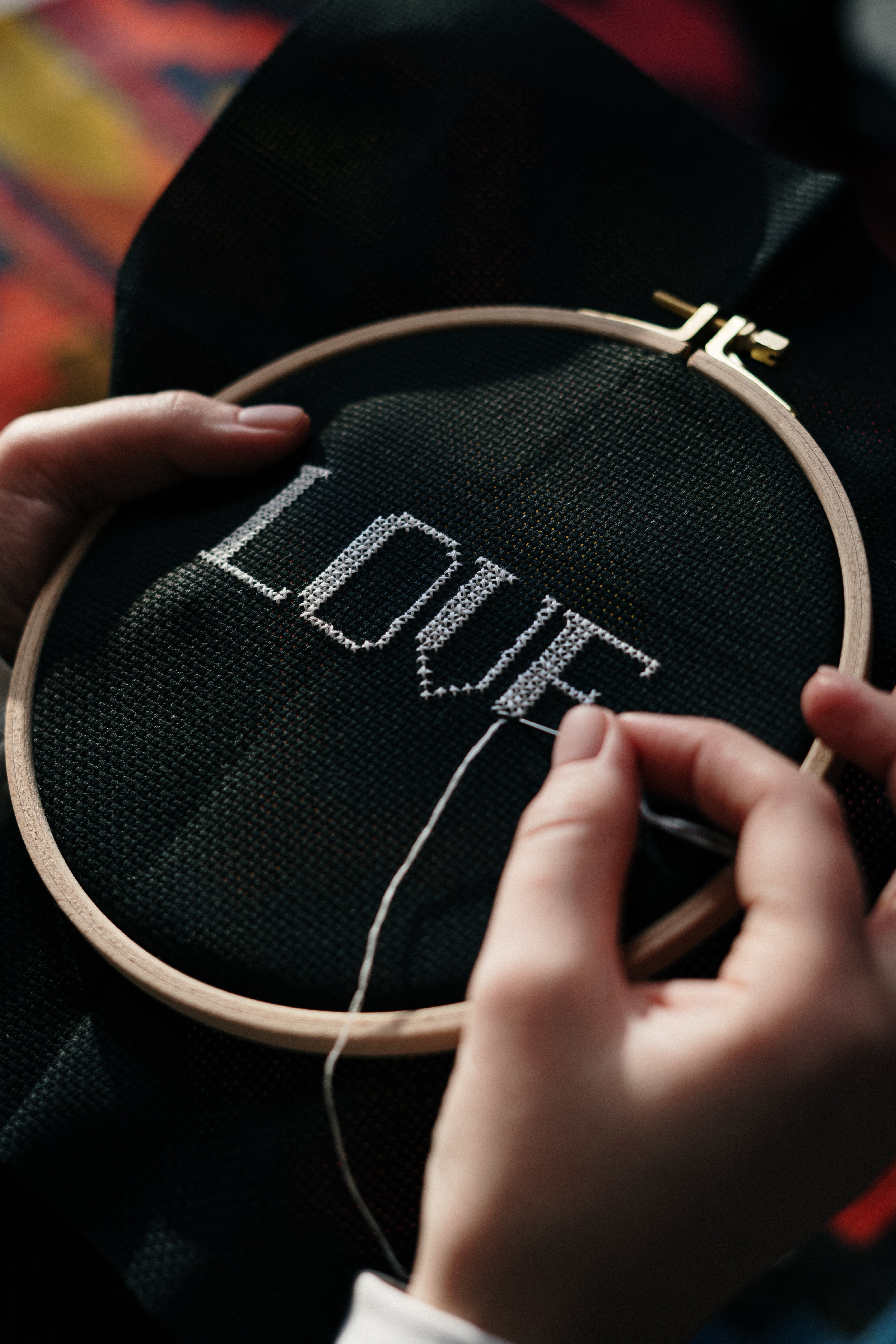 person-hand-embroidering-on-black-textile